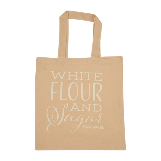 A beige tote bag with the text 'WHITE FLOUR AND SUGAR' printed in a cursive and elegant font on the front.